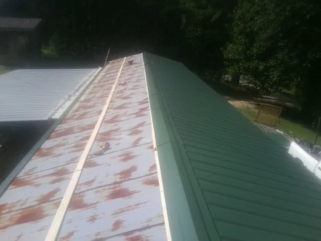 Old rusted panels beside newly installed green metal roofing — Wind Damage Roof Repair by Roofing Brothers in Old Bridge