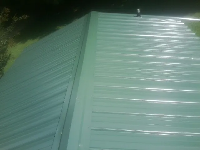 New green metal panels meeting at the ridge of a roof — Flat Roof Repair work by our crew in Old Bridge