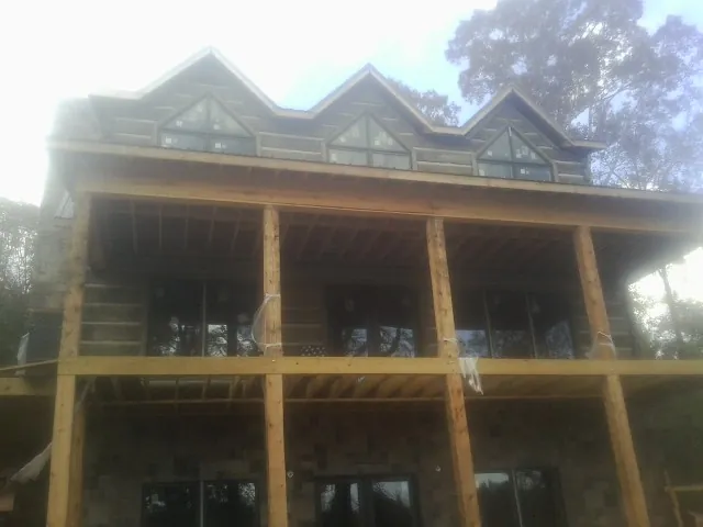 Dormers and porch framing on a large log home under construction — Roof Coating work by our crew in Old Bridge