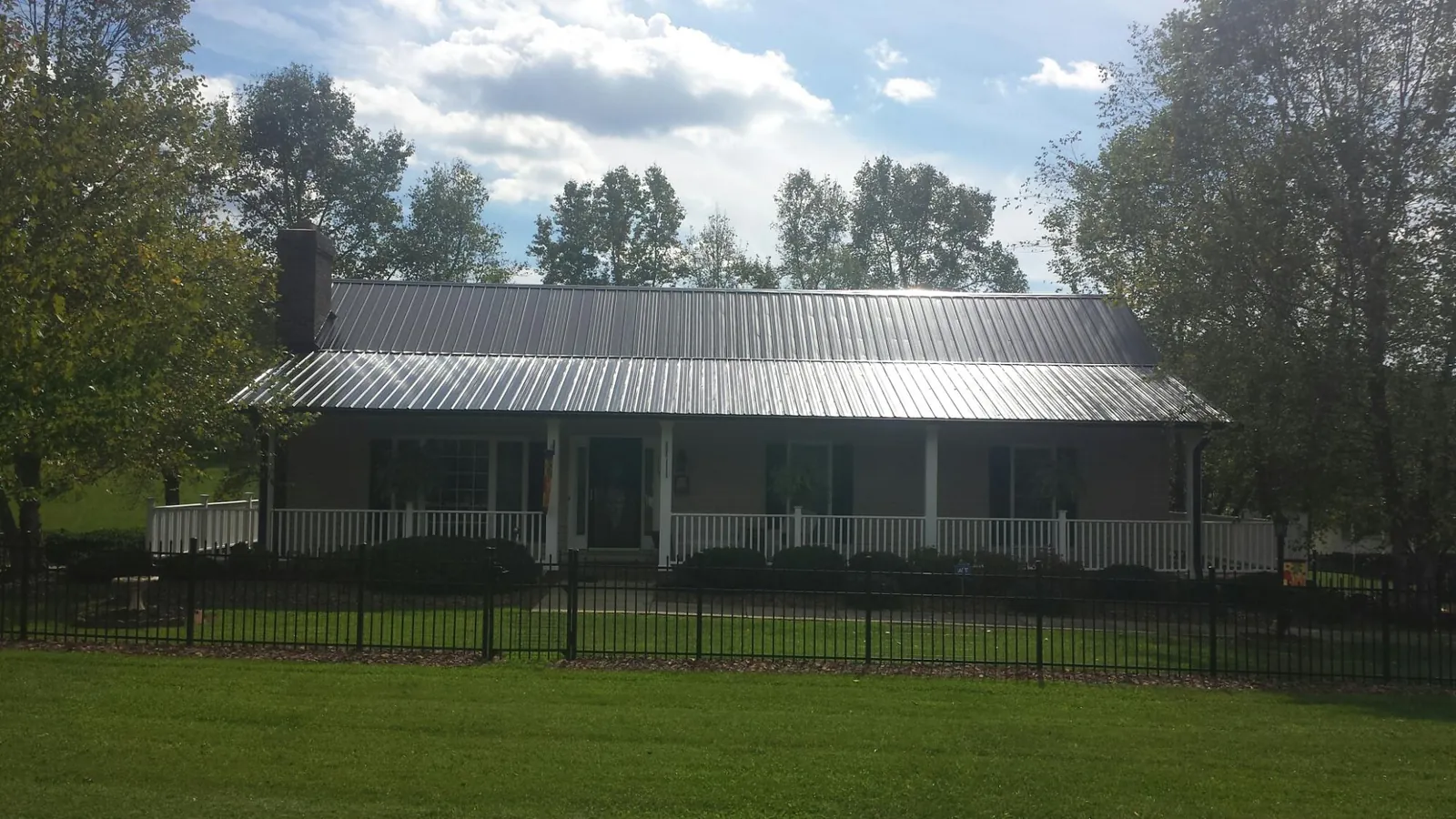 Gray metal roof on a brick ranch with a full width front porch — Gutter Guard Installation work by our crew in Old Bridge